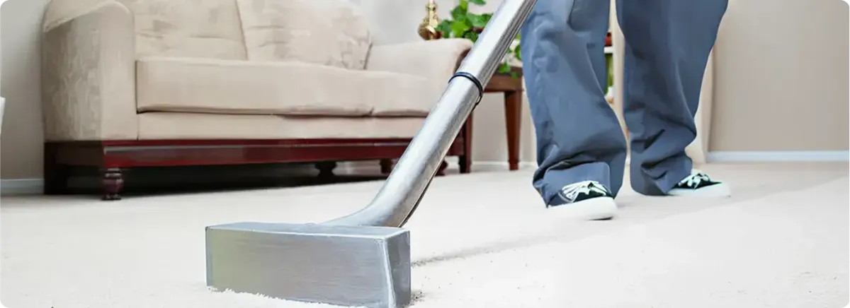 Carpet cleaning technician using a hot-water extraction wand on a light-colored carpet in a living room, Cleveland, OH.